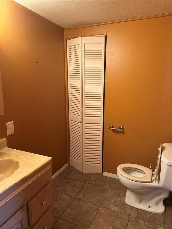 bathroom featuring tile patterned flooring, vanity, a textured ceiling, and toilet