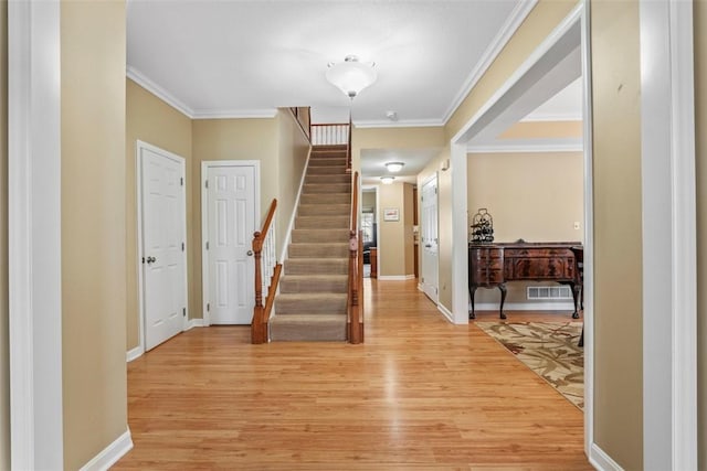 entryway with light hardwood / wood-style flooring and crown molding