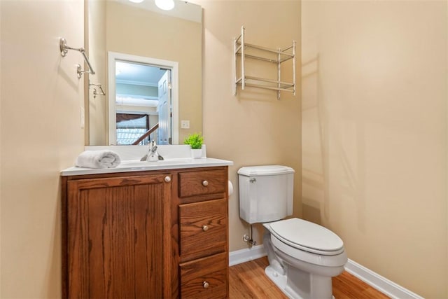 bathroom with hardwood / wood-style floors, vanity, toilet, and ornamental molding