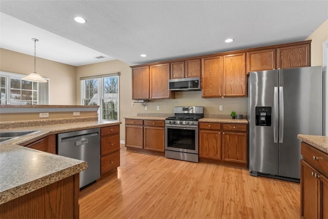 kitchen featuring light hardwood / wood-style flooring, stainless steel appliances, decorative light fixtures, and sink