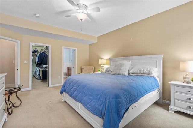 bedroom featuring a spacious closet, ceiling fan, ensuite bathroom, light colored carpet, and a closet