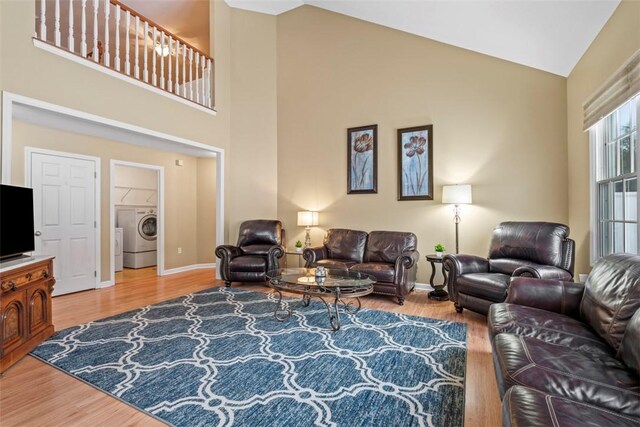 living room with hardwood / wood-style floors, high vaulted ceiling, and washer / dryer