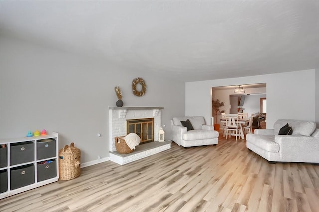 living room featuring light hardwood / wood-style flooring and a brick fireplace