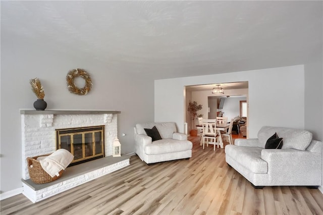 living room featuring light wood-type flooring and a fireplace