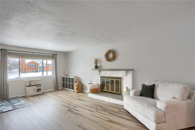 living room featuring light wood-type flooring and a brick fireplace