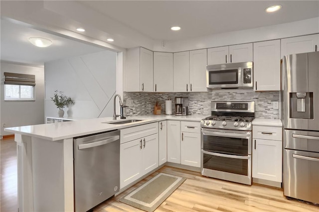 kitchen featuring white cabinetry, sink, kitchen peninsula, decorative backsplash, and appliances with stainless steel finishes