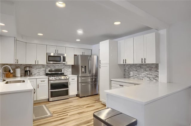 kitchen with decorative backsplash, appliances with stainless steel finishes, sink, light hardwood / wood-style flooring, and white cabinetry