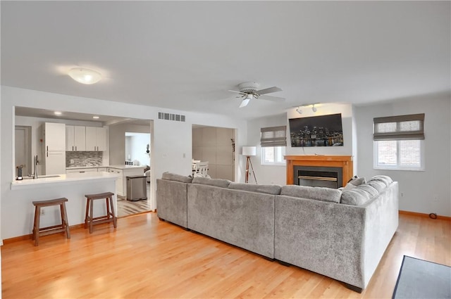 living room with ceiling fan, light hardwood / wood-style floors, and sink