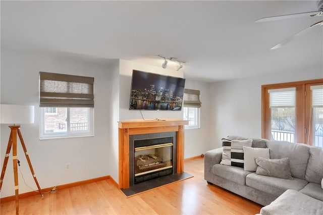 living room with a wealth of natural light, hardwood / wood-style floors, ceiling fan, and track lighting