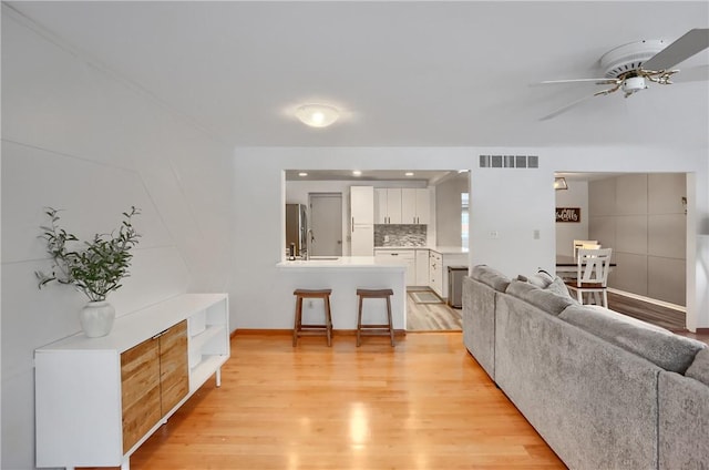 living room with light hardwood / wood-style floors, ceiling fan, and sink