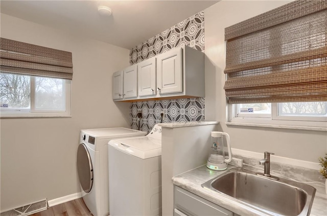 laundry room featuring separate washer and dryer, a healthy amount of sunlight, sink, and cabinets