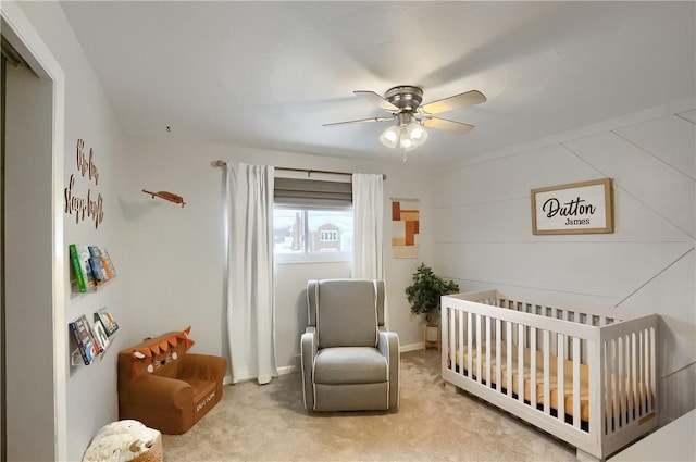 carpeted bedroom featuring ceiling fan and a nursery area