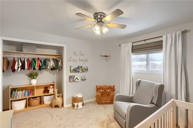 carpeted bedroom featuring a nursery area, a closet, and ceiling fan