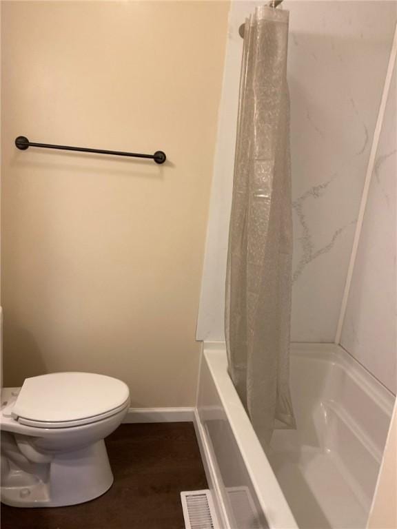 bathroom featuring toilet, shower / bath combination with curtain, and hardwood / wood-style floors