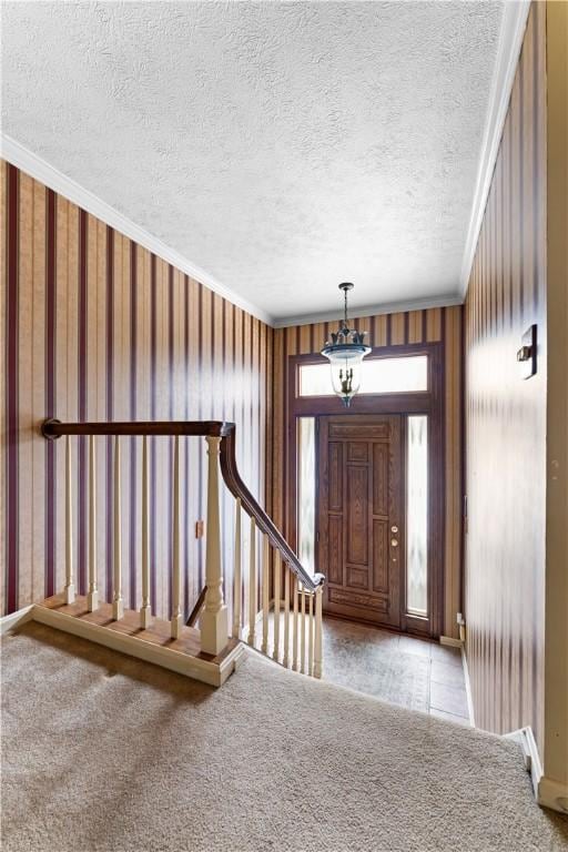 foyer with light carpet, a textured ceiling, and ornamental molding