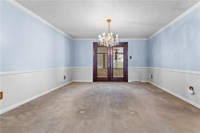 carpeted empty room with crown molding, french doors, a textured ceiling, and an inviting chandelier