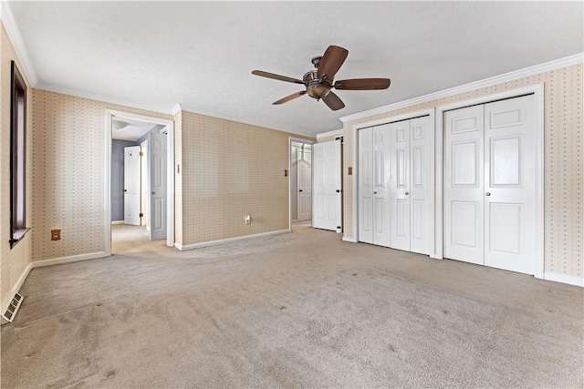 unfurnished bedroom featuring carpet flooring, ceiling fan, and crown molding