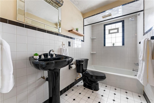 bathroom with tiled shower / bath combo, toilet, and tile walls