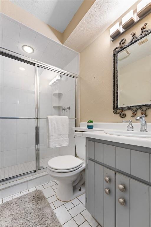 bathroom featuring vanity, tile patterned flooring, toilet, a textured ceiling, and an enclosed shower