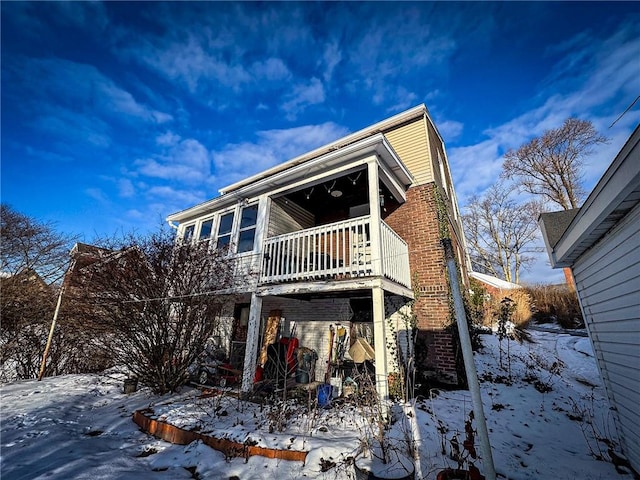 snow covered rear of property featuring a balcony