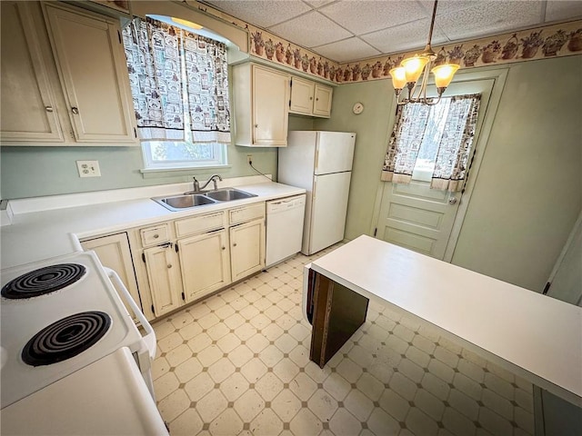 kitchen with a sink, white appliances, an inviting chandelier, light countertops, and light floors