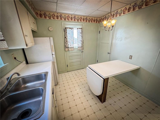 kitchen with sink, a drop ceiling, and decorative light fixtures