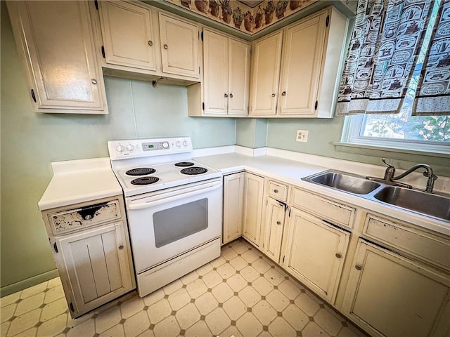 kitchen featuring light floors, light countertops, cream cabinets, white range with electric stovetop, and a sink