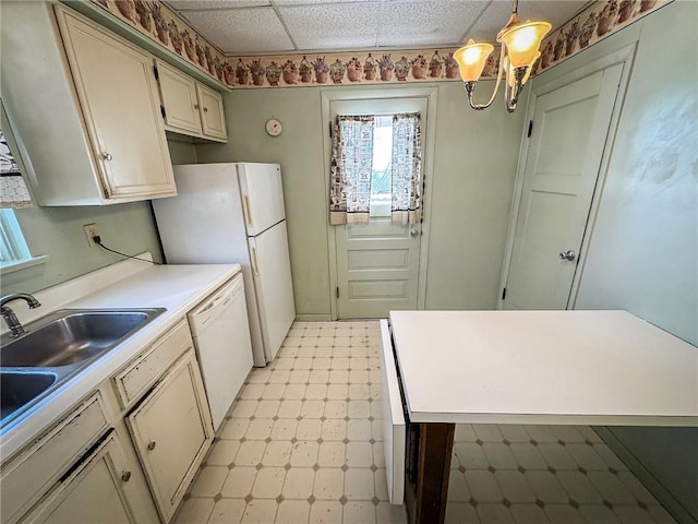 kitchen with decorative light fixtures, light floors, light countertops, white appliances, and a sink