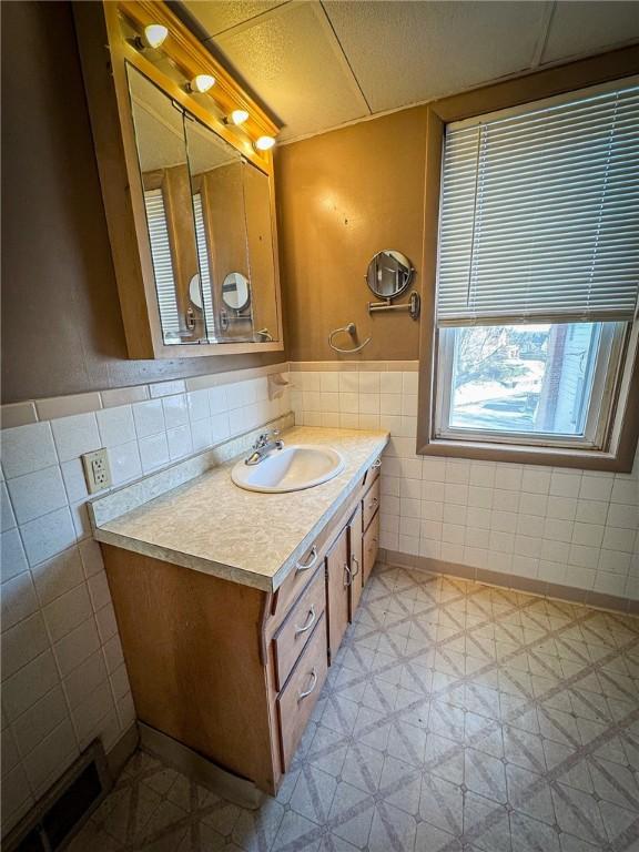 bathroom featuring vanity and tile walls