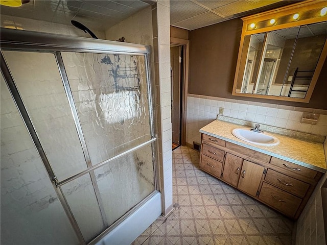 full bathroom featuring vanity, wainscoting, a stall shower, tile patterned floors, and tile walls