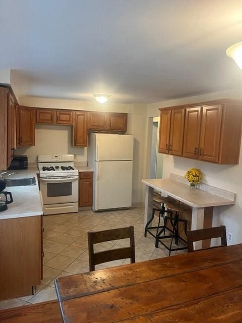 kitchen featuring sink, light tile patterned floors, and white appliances