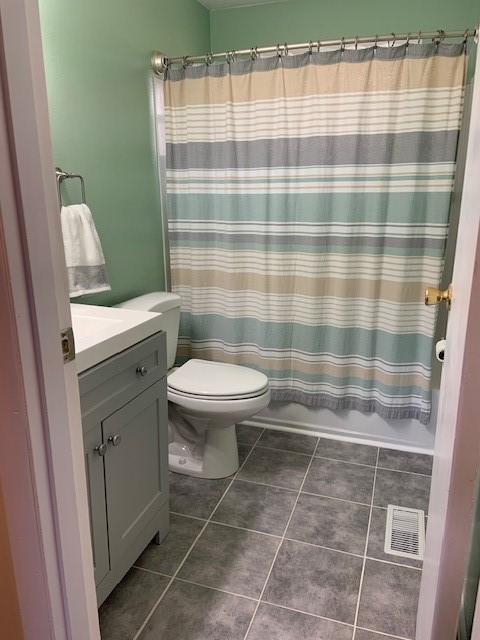 full bathroom featuring tile patterned flooring, vanity, toilet, and shower / bathtub combination with curtain