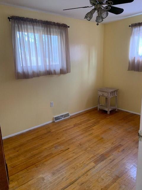 unfurnished room featuring hardwood / wood-style flooring, plenty of natural light, and ceiling fan