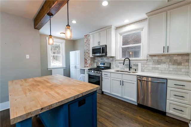 kitchen featuring pendant lighting, wooden counters, sink, tasteful backsplash, and stainless steel appliances