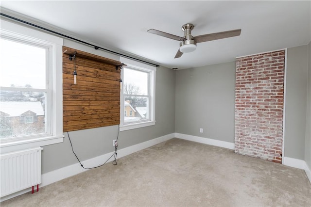 carpeted empty room with ceiling fan and radiator heating unit