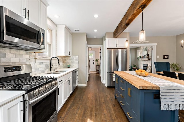 kitchen featuring wooden counters, white cabinets, blue cabinets, appliances with stainless steel finishes, and decorative light fixtures