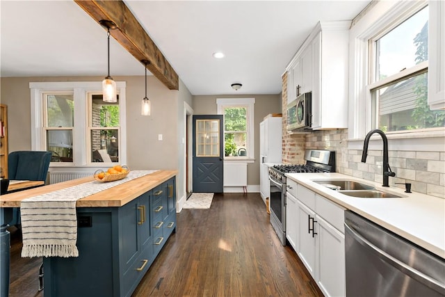 kitchen featuring white cabinetry, sink, wood counters, pendant lighting, and appliances with stainless steel finishes