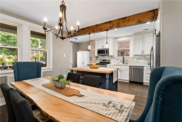 dining space featuring dark hardwood / wood-style flooring, sink, beamed ceiling, and a chandelier