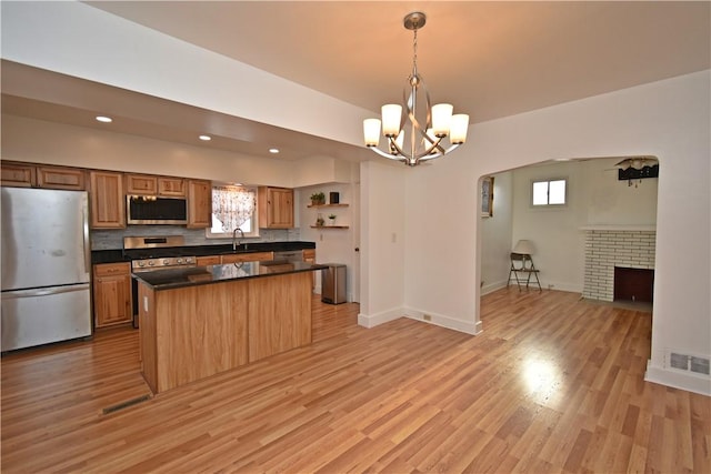 kitchen featuring stainless steel appliances, sink, light wood-type flooring, and decorative light fixtures