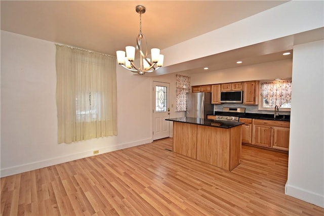 kitchen featuring sink, decorative light fixtures, a center island, light wood-type flooring, and appliances with stainless steel finishes