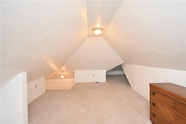 bonus room featuring lofted ceiling, light colored carpet, and a textured ceiling