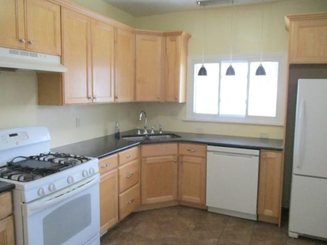 kitchen with white appliances, sink, hanging light fixtures, dark tile patterned floors, and light brown cabinetry