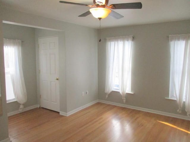 spare room featuring a wealth of natural light, ceiling fan, and light hardwood / wood-style flooring