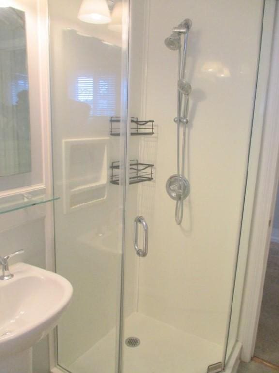 bathroom with a shower with shower door and sink