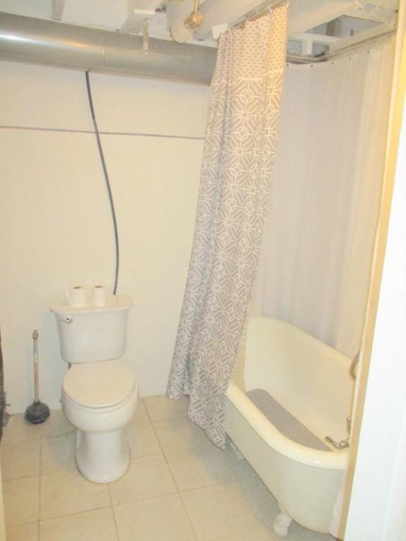 bathroom with toilet, tile patterned floors, and shower / tub combo with curtain