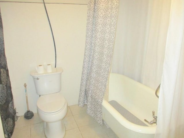 bathroom featuring tile patterned flooring, shower / bath combo, and toilet