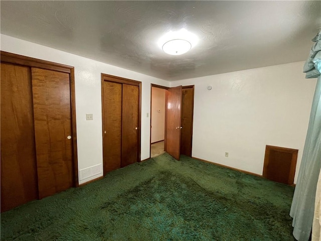 unfurnished bedroom with two closets and carpet flooring