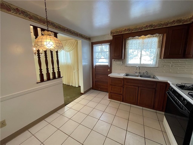 kitchen with light tile patterned floors, white gas range oven, decorative backsplash, sink, and decorative light fixtures