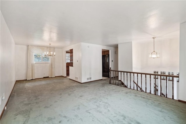 carpeted spare room featuring a chandelier, visible vents, and baseboards