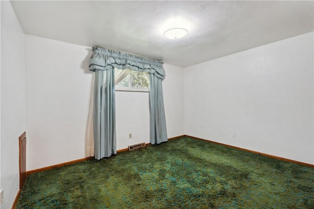 empty room with baseboards, visible vents, and dark carpet